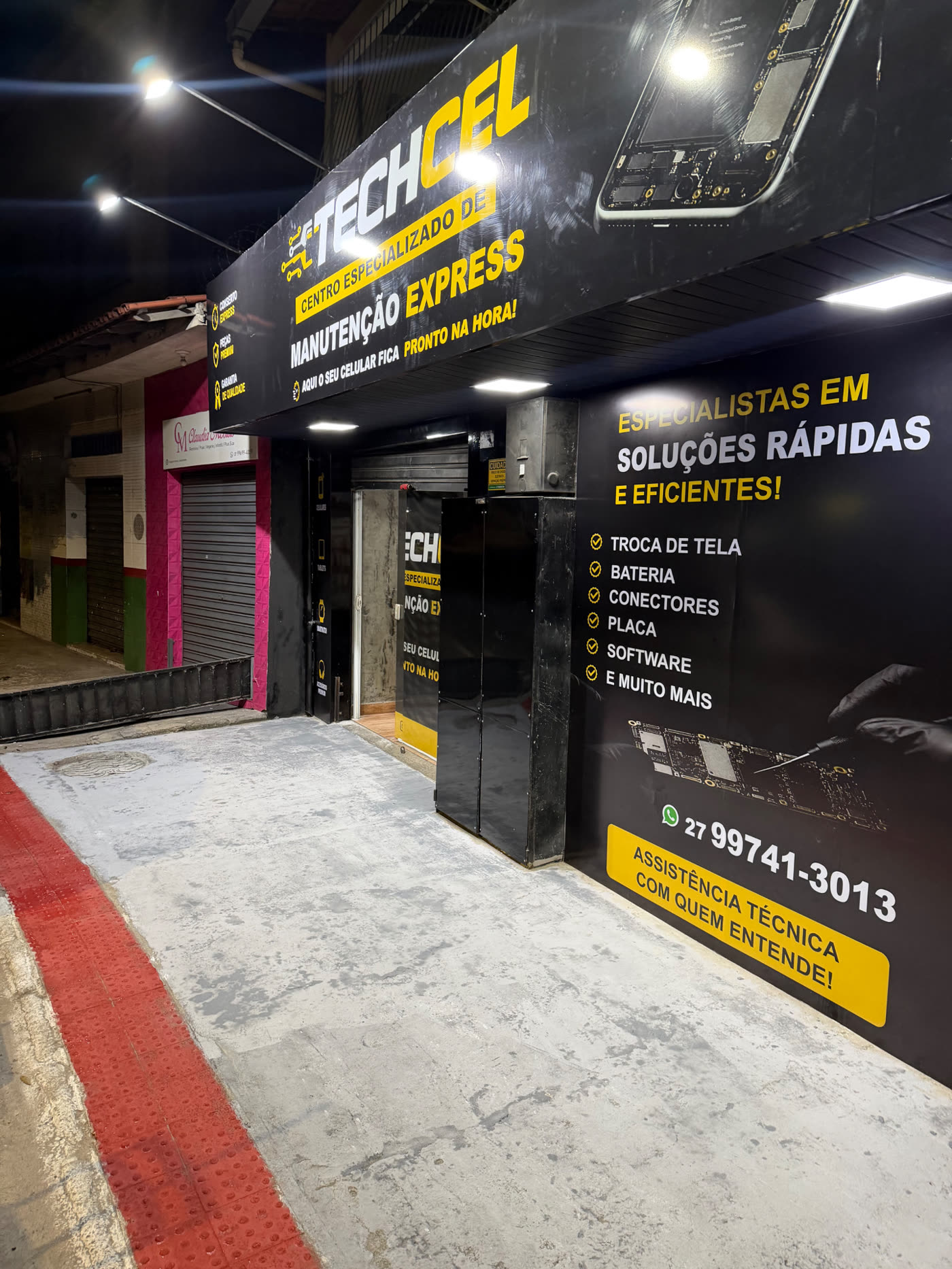 Fachada iluminada da TECHCEL à noite, com letreiro Manutenção Express