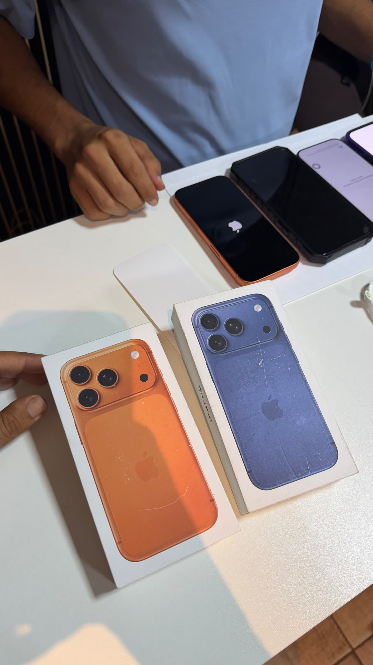 iPhones lacrados nas cores laranja e azul sobre a bancada da TECHCEL